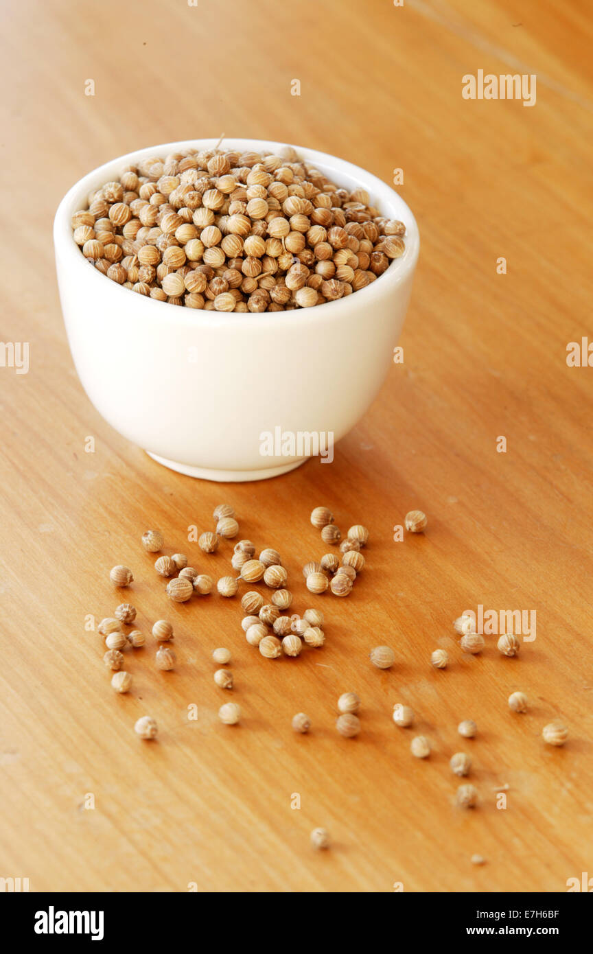 A small bowl of coriander seeds on a wooden table surface. Stock Photo