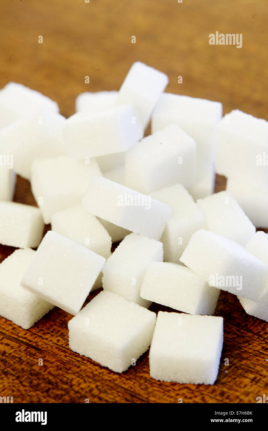 White sugar cubes in a pile on a wood surface. Stock Photo