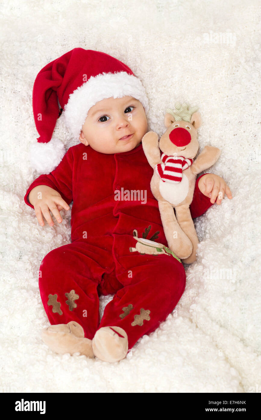 Little cute baby boy, dressed in red overall with santa hat ...