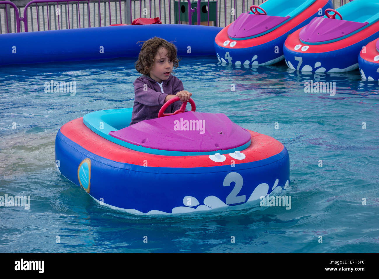 Young Boy Concentrating in Electric Fun Fair Boat Stock Photo