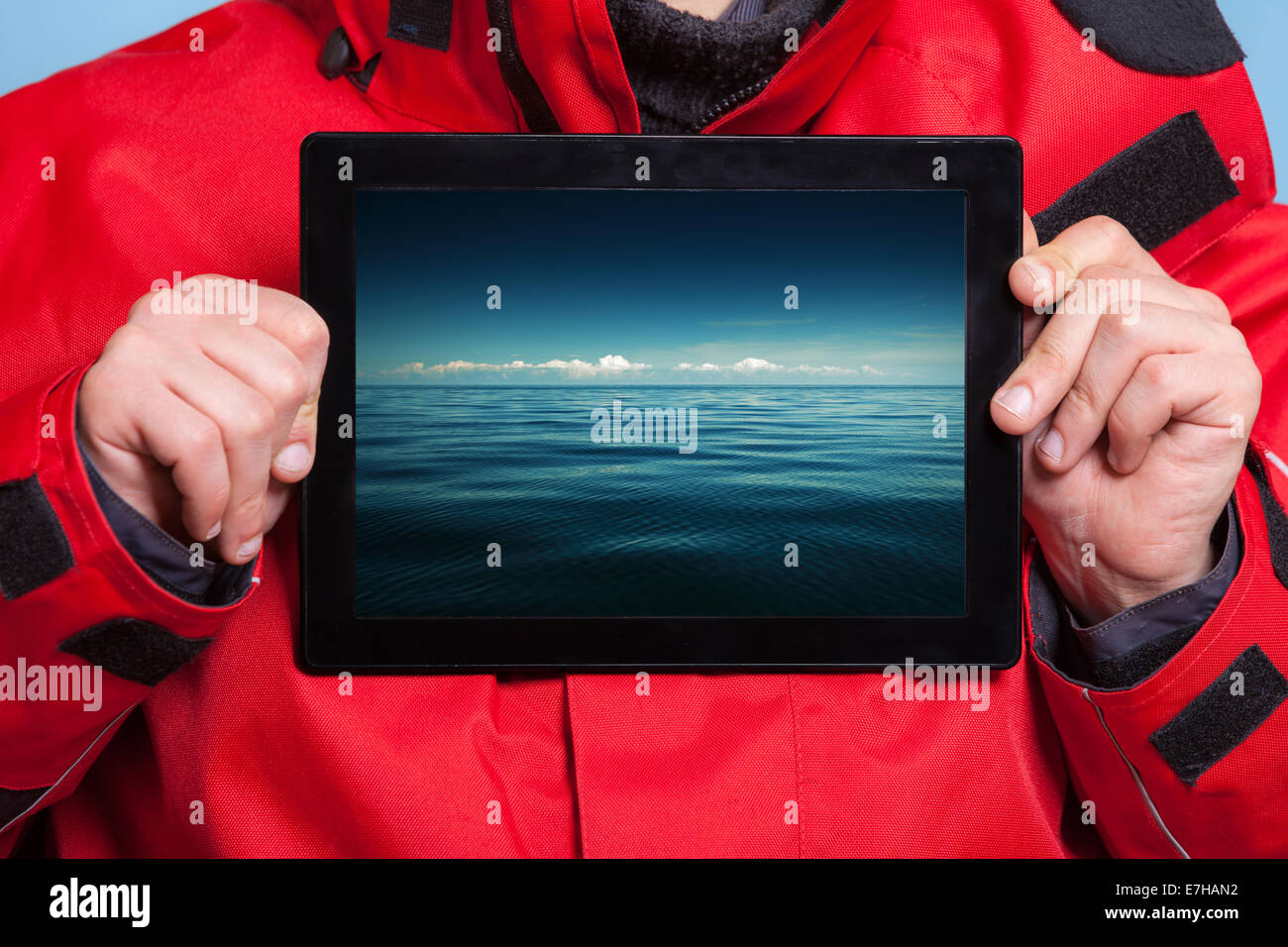 Closeup of male hands holding ipad with photo of stormy sea. Man showing screen tablet touchpad dreaming about holiday vacation. Stock Photo