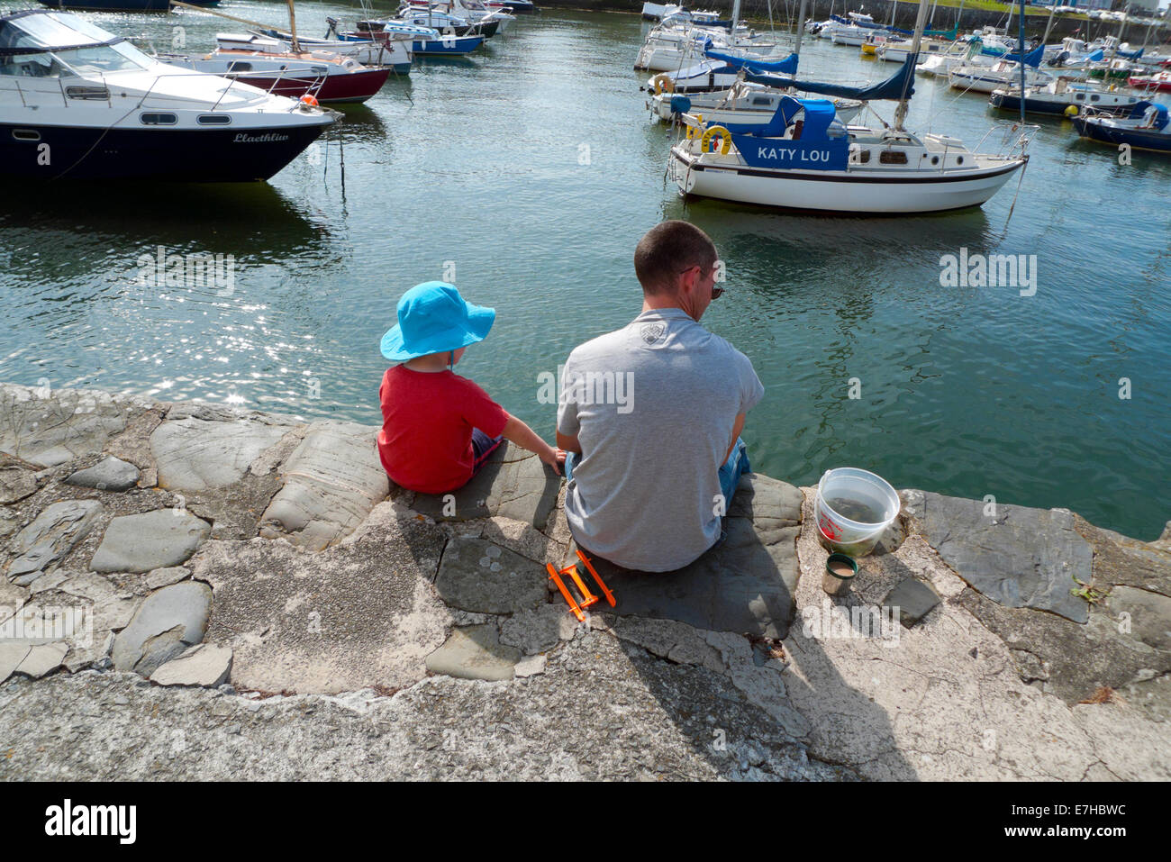 Father and son sitting on the quay at Aberaeron Harbour, Ceredigion with a pot of crabs Wales UK KATHY DEWITT Stock Photo