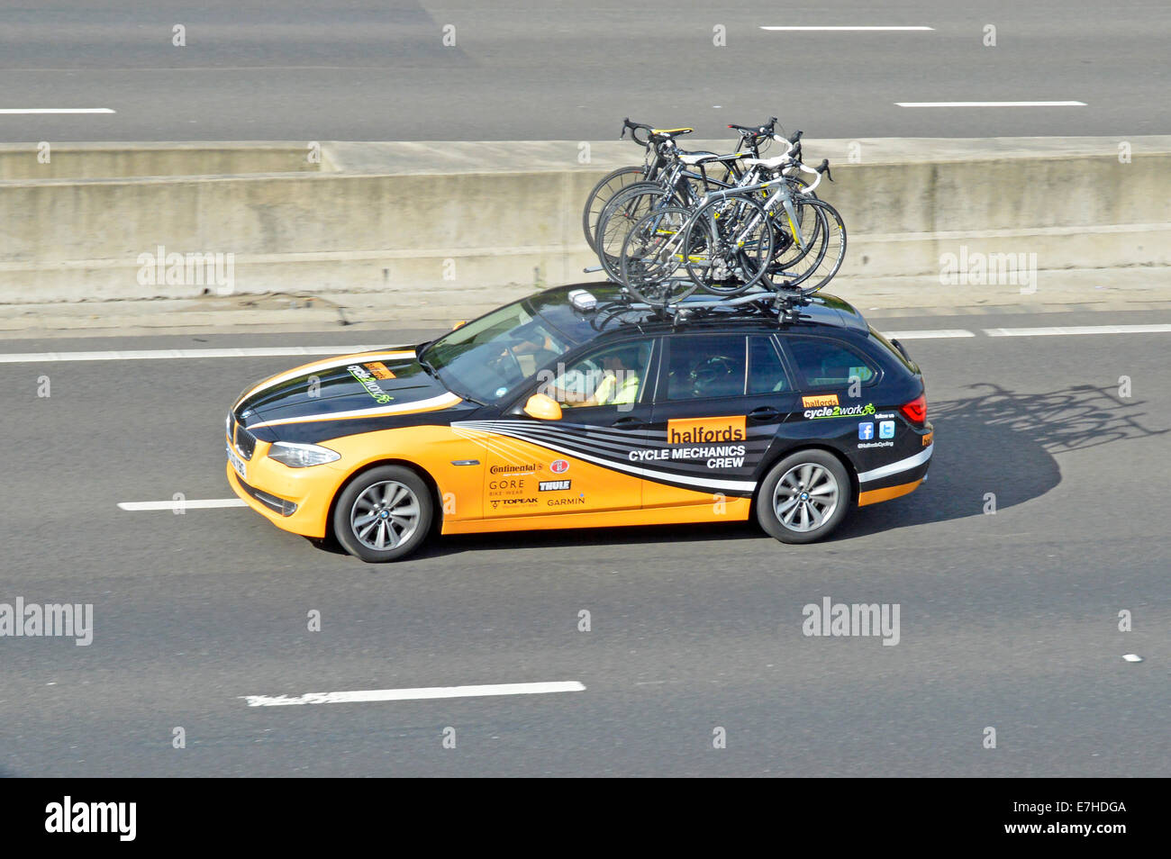 Halfords Cycle Mechanics crew car on motorway with bikes loaded on roof rack and advertising on bodywork Stock Photo