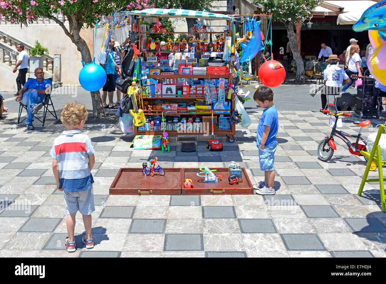 Children mesmerised by display of moving toys beside a stall in Taormina main square Province of Messina Sicily Italy Stock Photo