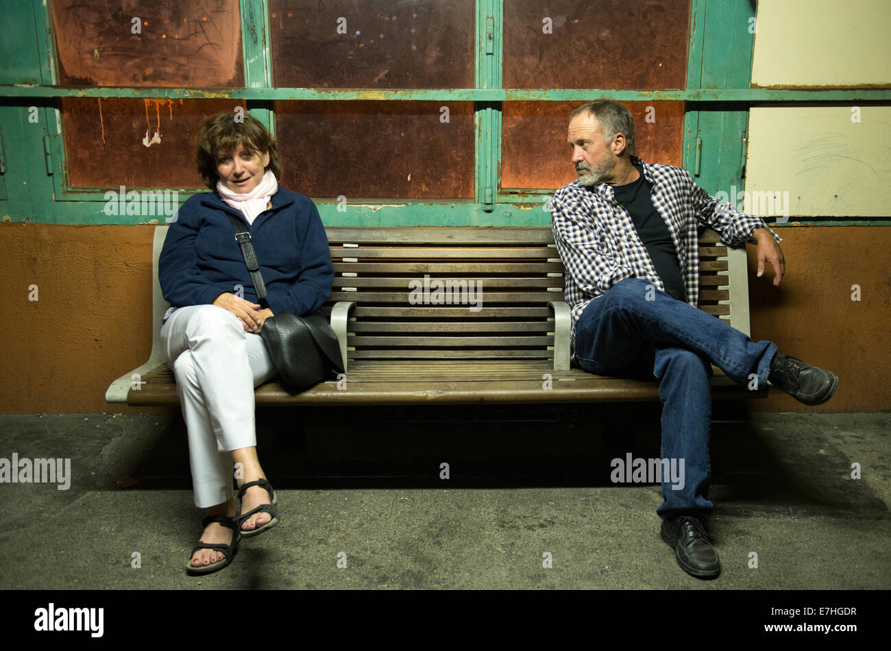 Man ogling woman on a bench while waiting for a train Stock Photo