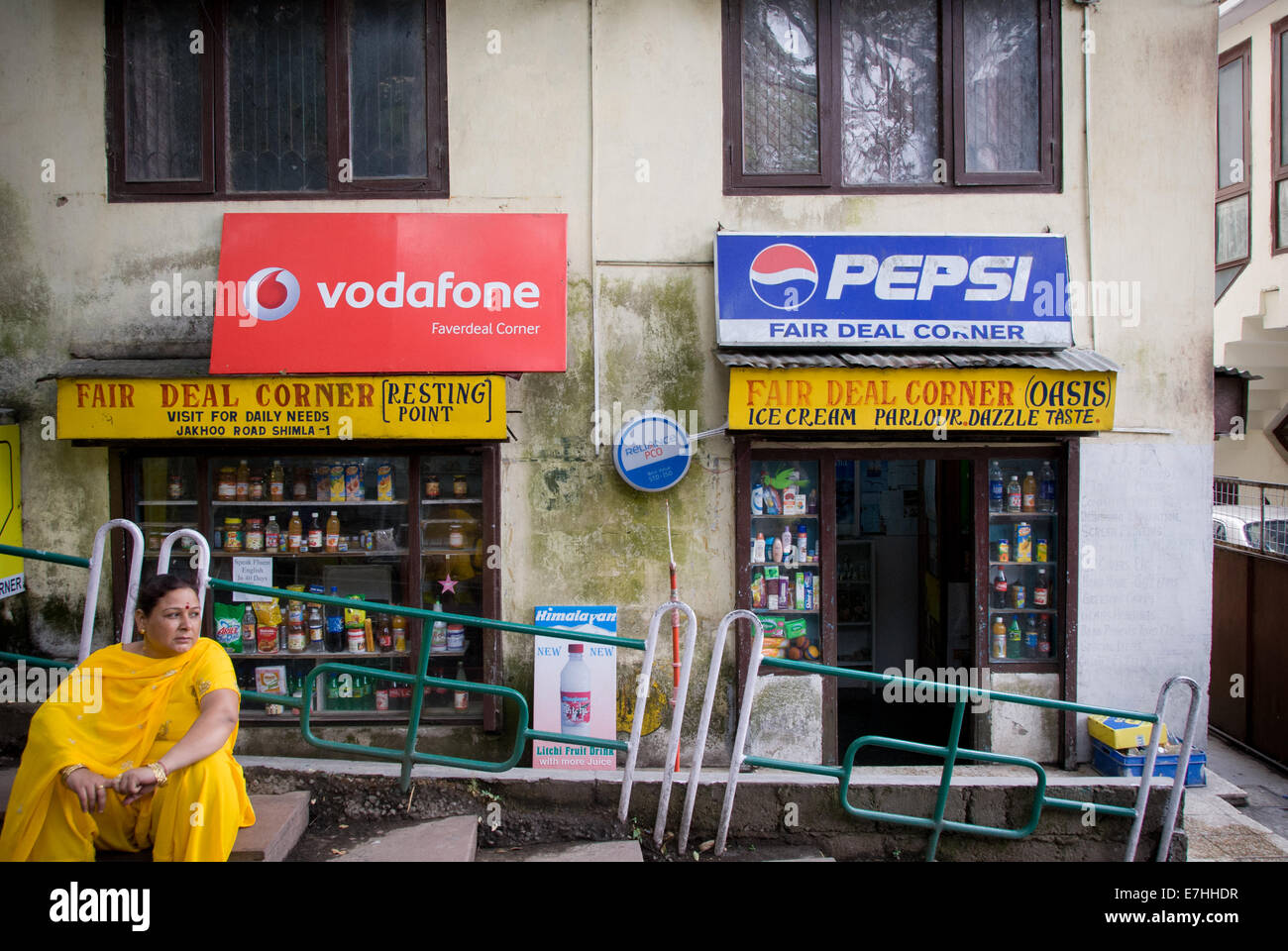 Indian woman in sari in front of billboards for Western companies in Shimla India Stock Photo