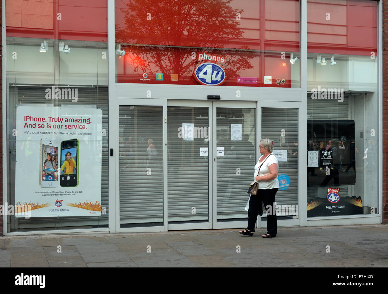 a woman walks past the closed shop of Phones4U, which went into liquidation through Vodafone and EE not renewing contracts. Stock Photo
