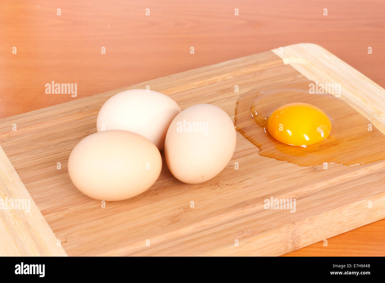 Three brown eggs closeup and one broken on wooden background Stock Photo