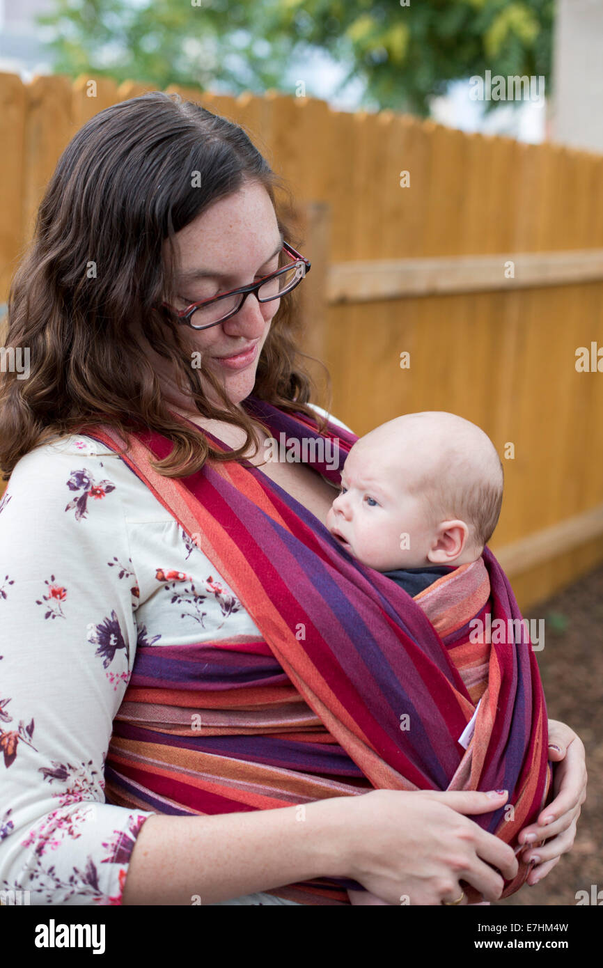 Denver, Colorado - A 26-year-old woman carries her two-month-old son in a baby carrier wrap. Stock Photo