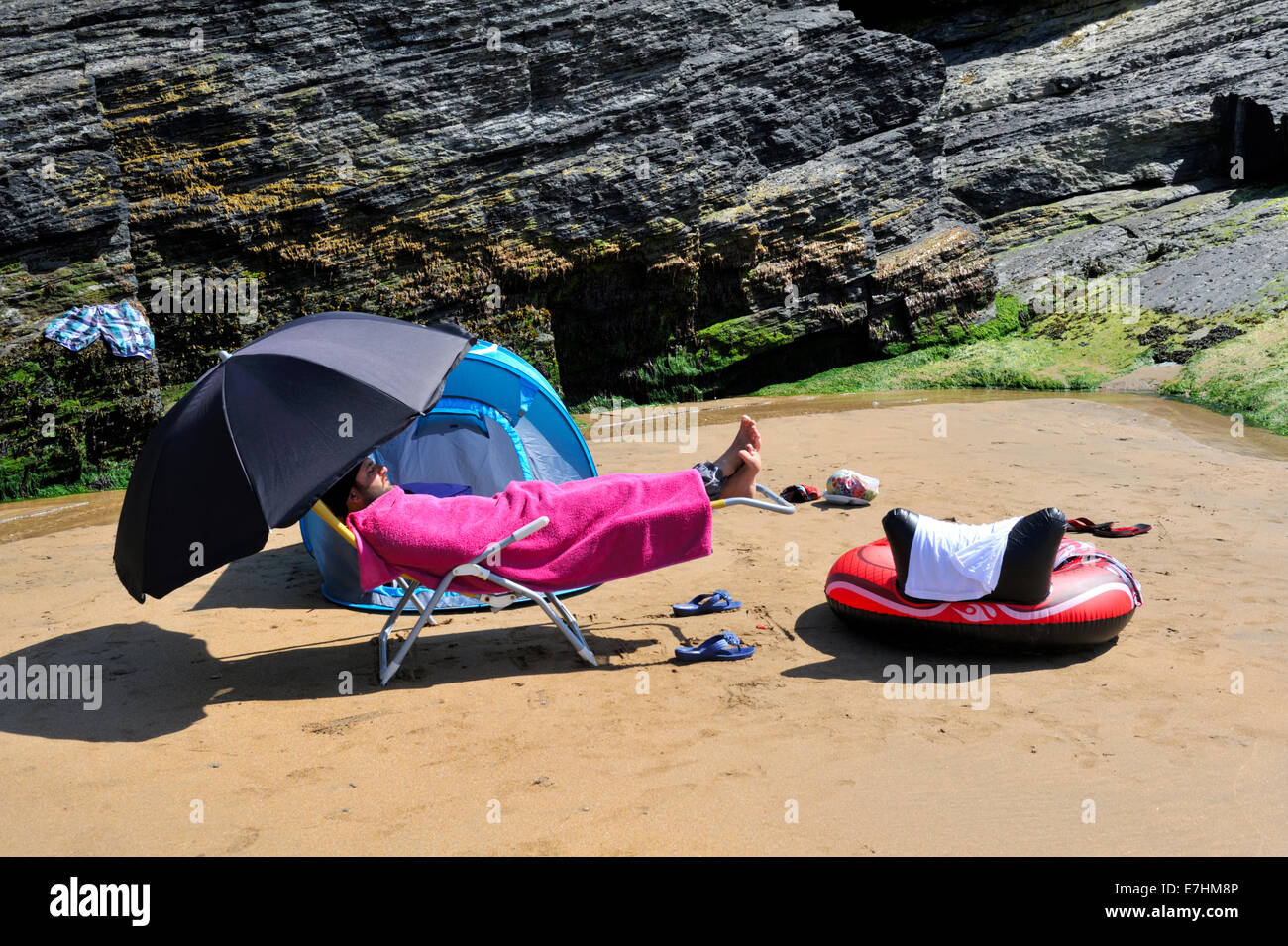 Man covered up on British beach for the summer visit Stock Photo