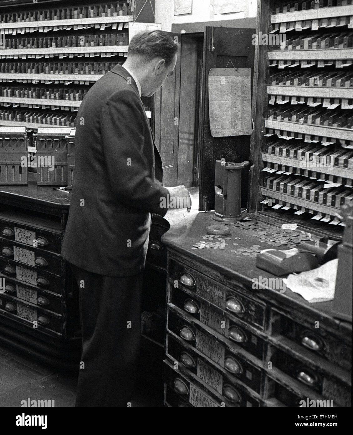 1950s, Historical picture of a railway ticket office selling tickets for train travel with attendant and coins on the counter. Stock Photo