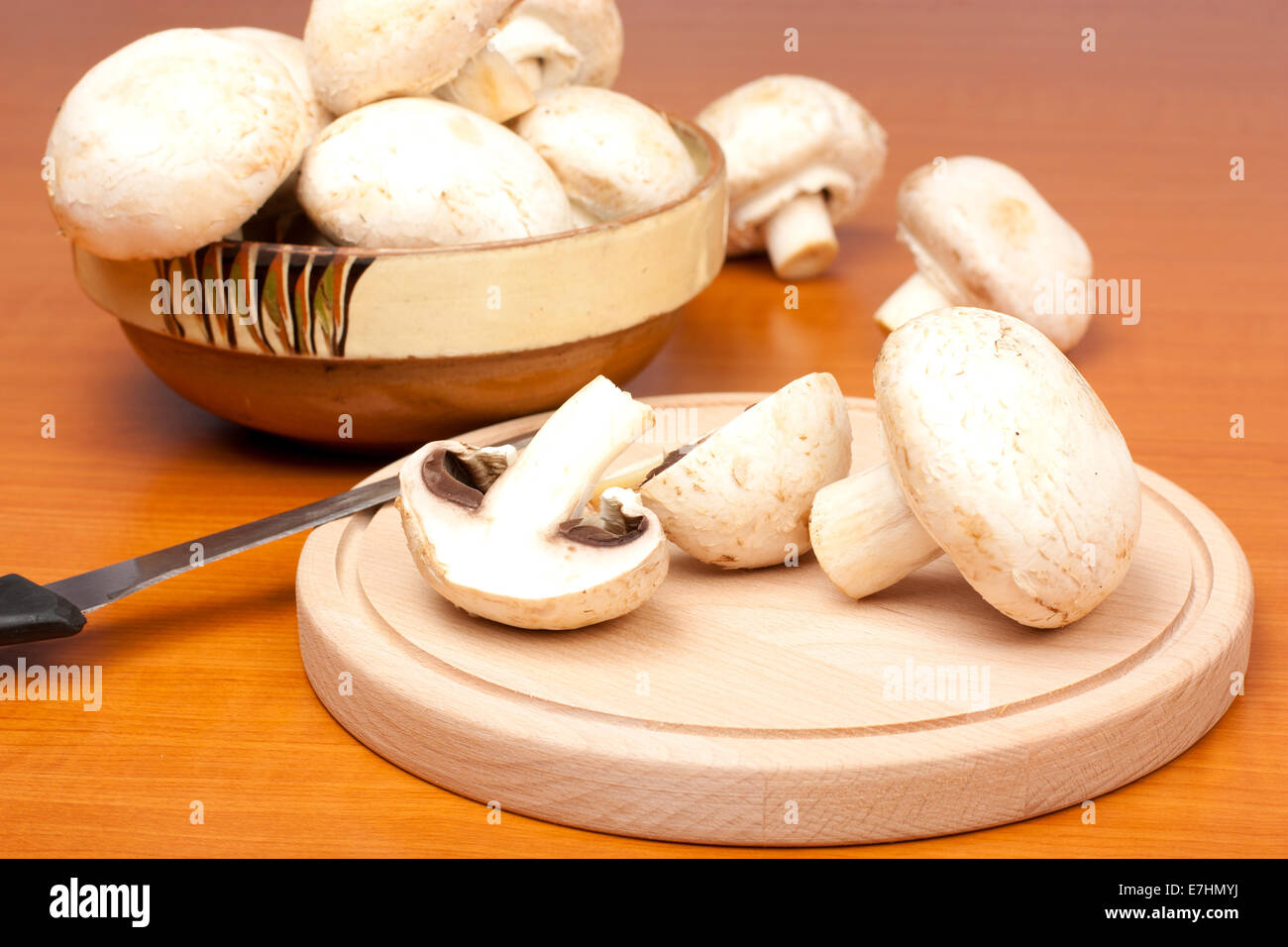 Mushrooms on a cutting board with a knife on wood background Stock Photo