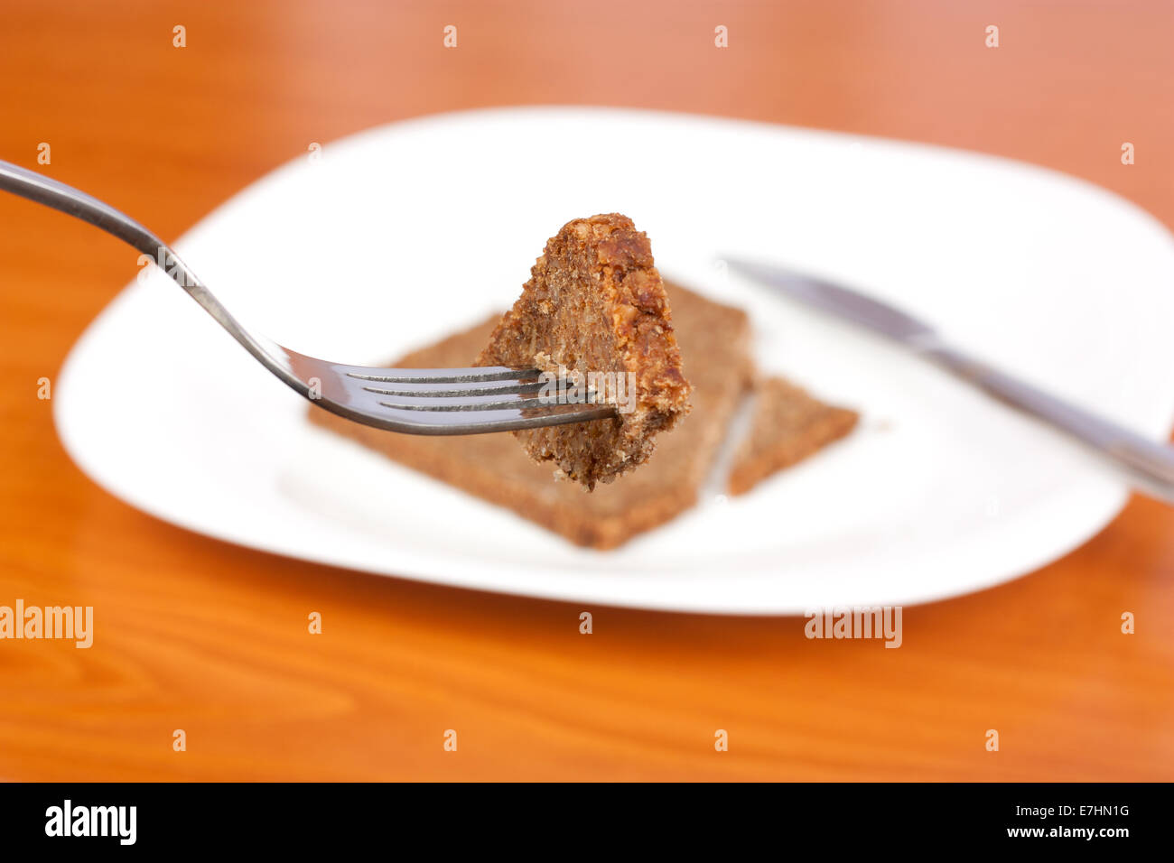 Rye bread in fork and one plate and knife in background Stock Photo