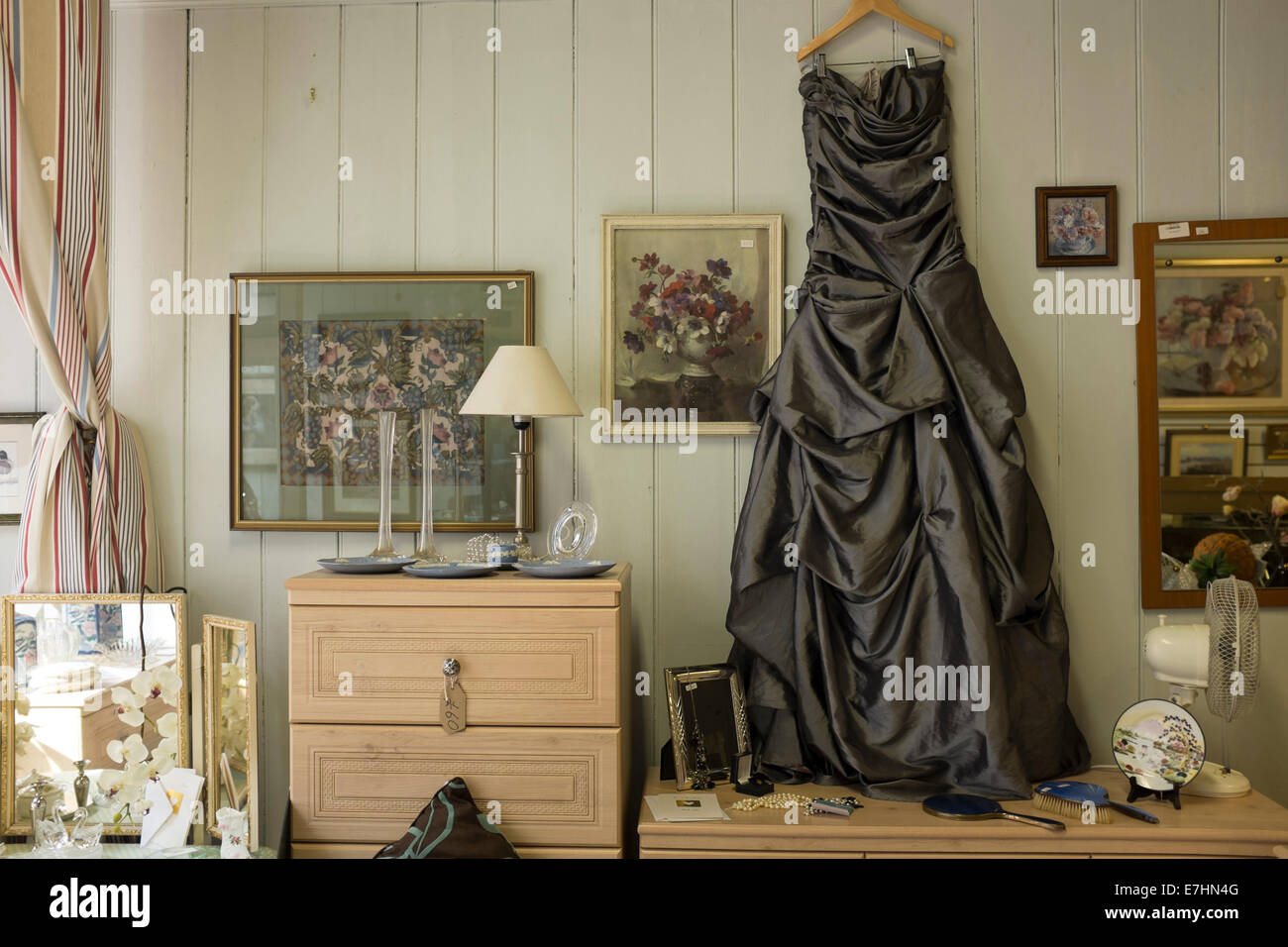 Beautiful old dress in charity shop display with various objects and pictures Stock Photo