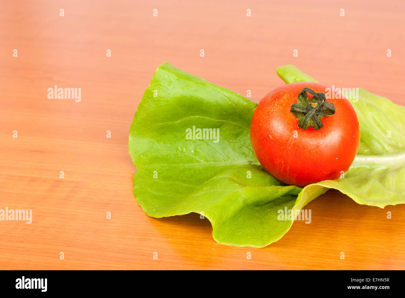 Tomato on lettuce leaf on kitchen table Stock Photo