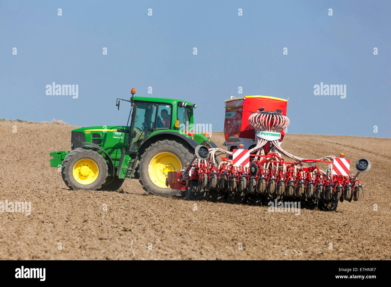 John Deere tractor sowing seed on a field, grain wheat, seasonal work, Czech Republic Farmer agriculture machinery sowing machine seed drill tractor Stock Photo