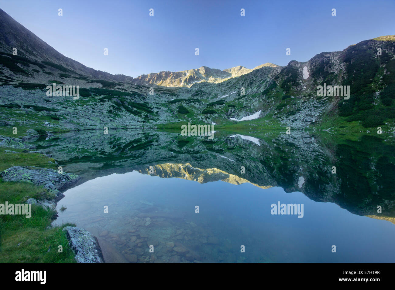 Morning reflection in an alpine glacial lake in the Retezat National Park, Carpathian Mountains, Romania Stock Photo