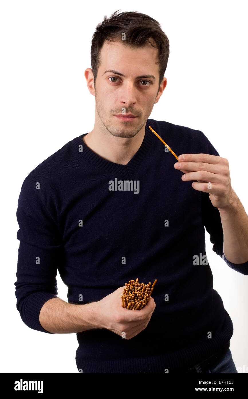 Young man eating salty sticks isolated over white background Stock Photo