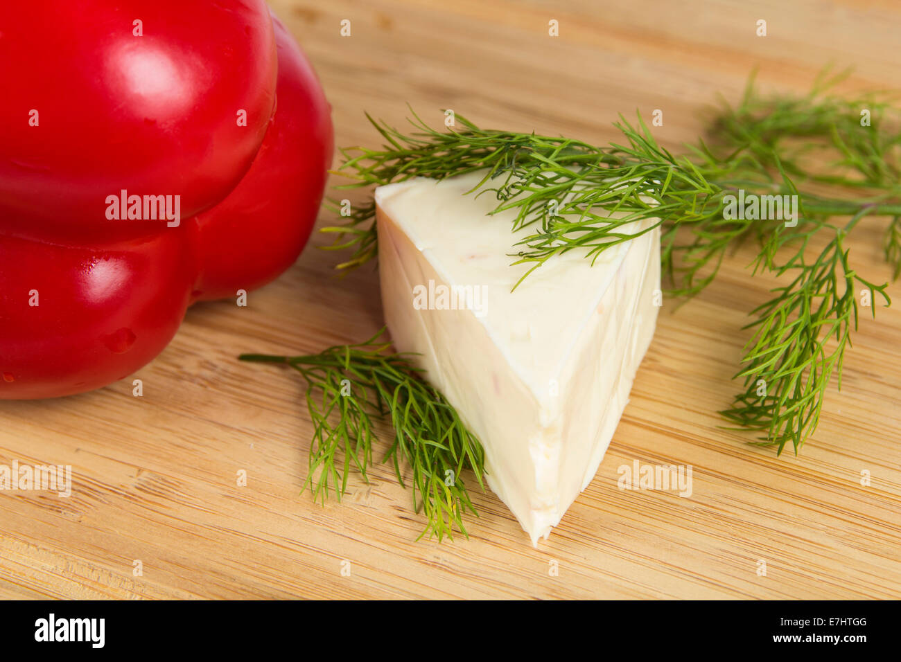 Triangle piece of cheese with dill and pepper on wooden board Stock Photo