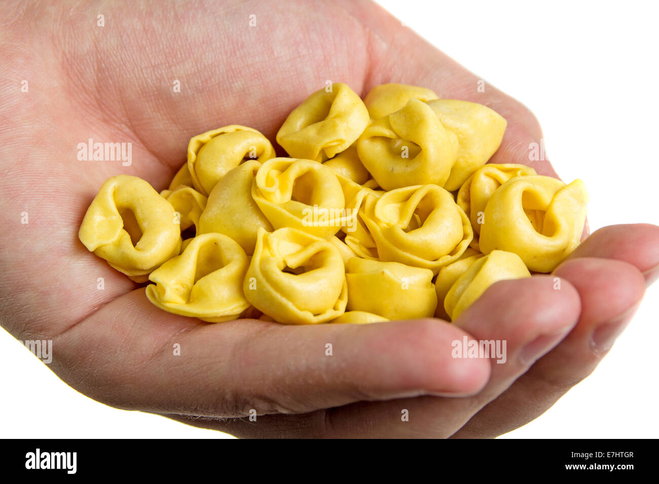 Hand with Italian tortellini pasta isolated on white background Stock