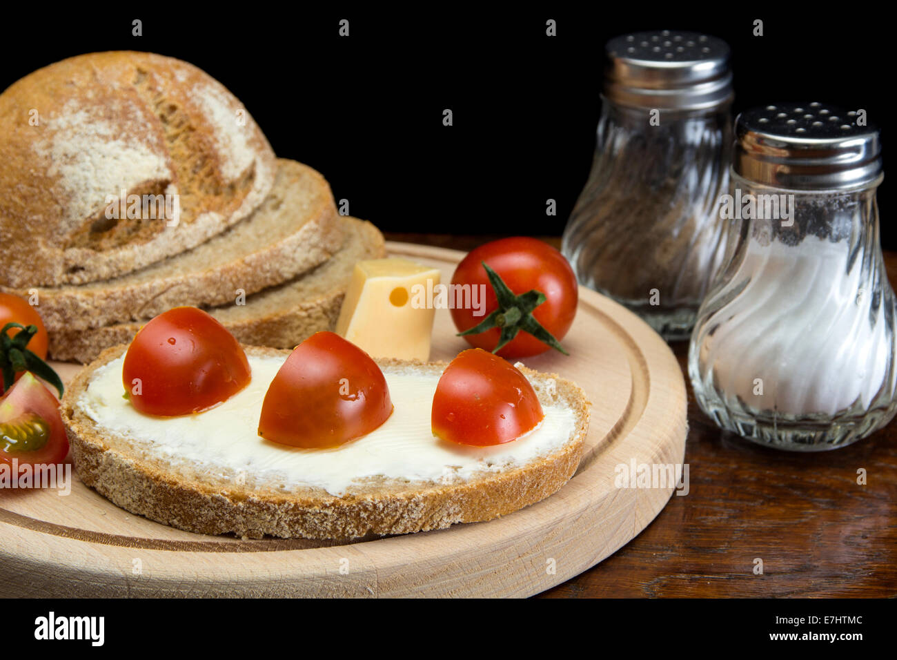 Close up image of spreading cream cheese on pumpernickel bread and splices tomato Stock Photo