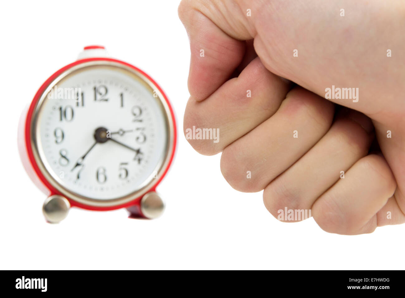 Man's hand in a fist about to hit a red alarm clock isolated on white Stock Photo