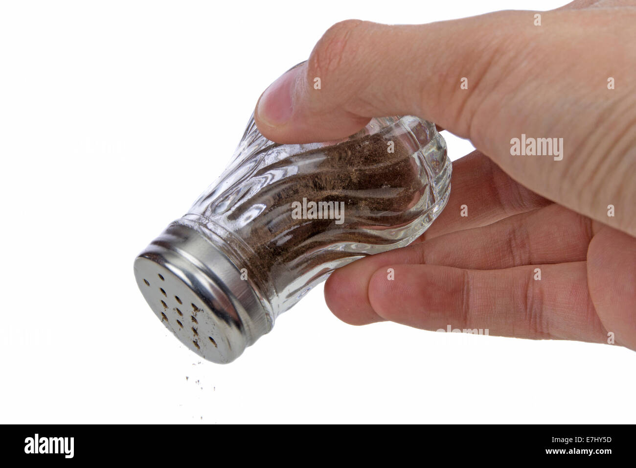 Hand holding pepper shaker up side down isolated on white background