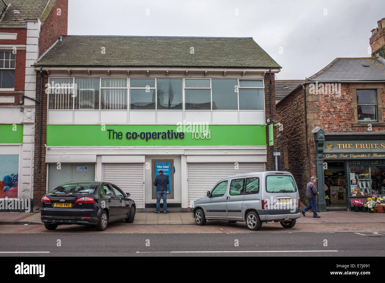 A man at a cash machine ATM at the Co-operative food Supermarket in Amble, Northumberland UK Stock Photo