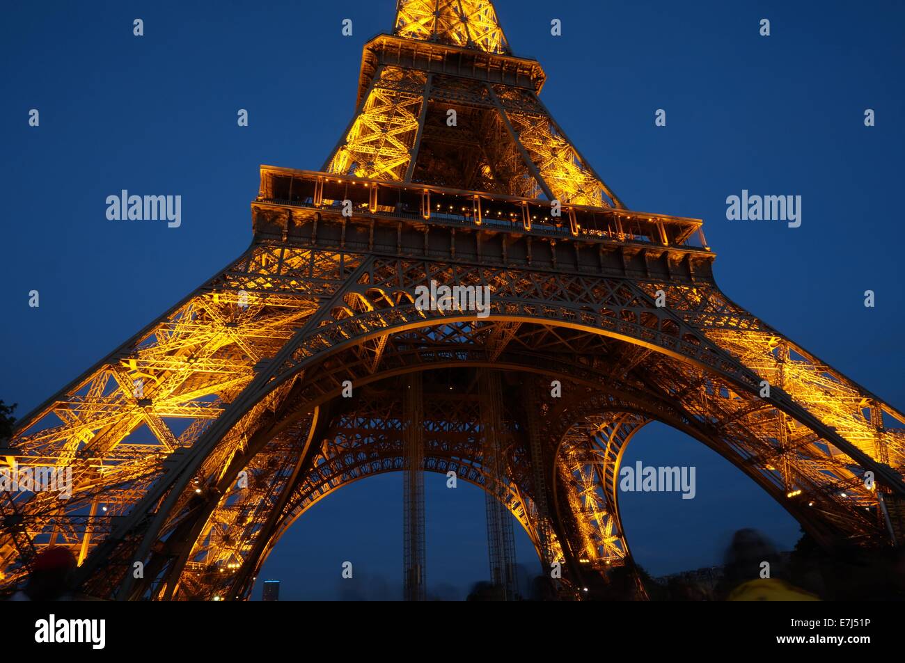Eiffel Tower lit up in golden color by night against a deep blue sky