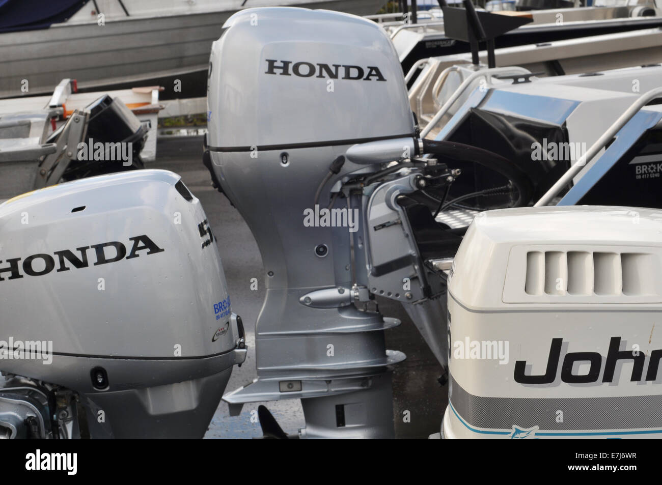 Various outboard engines on transoms of recreational vessels in boat yard ready for sale Stock Photo