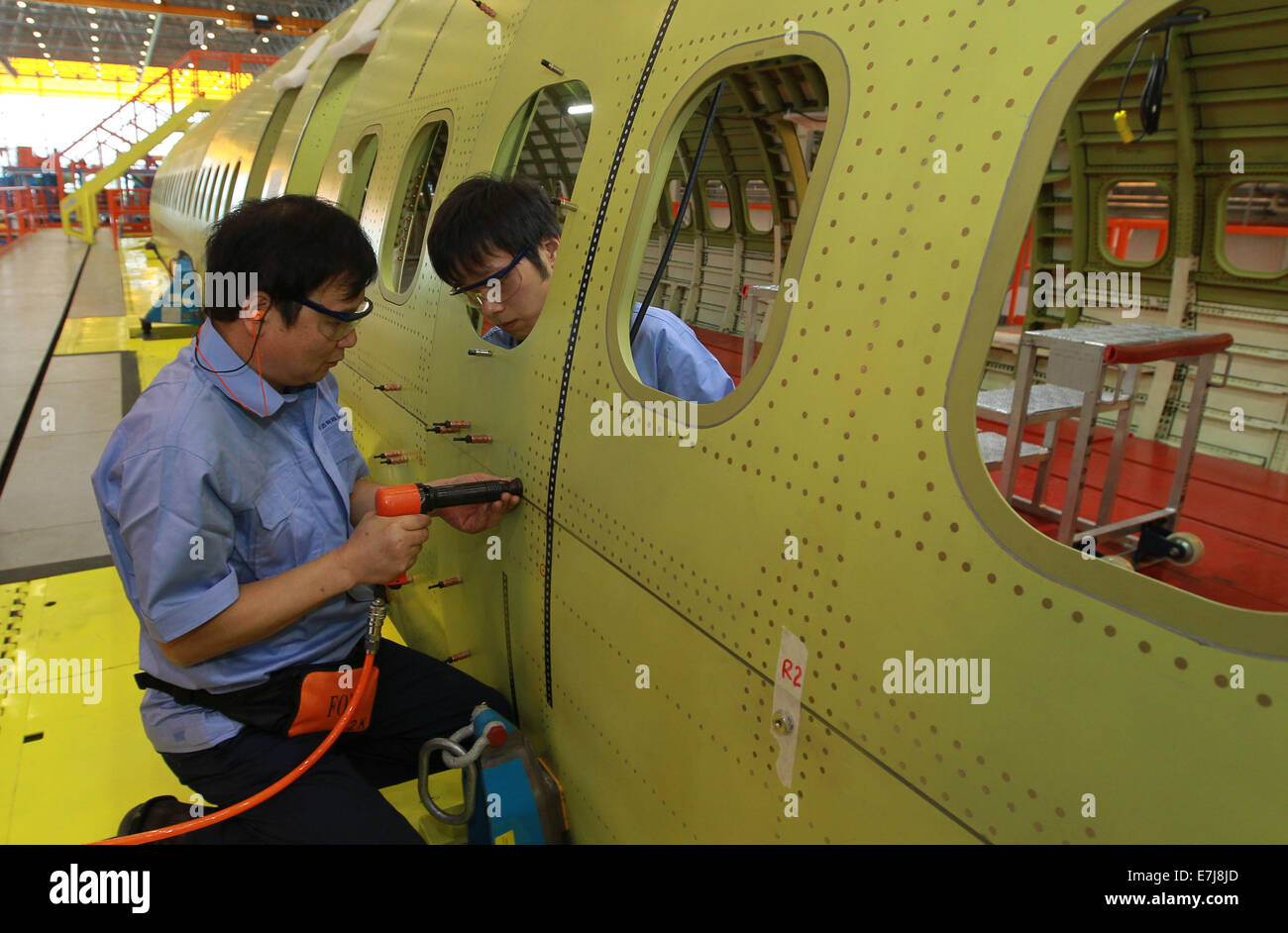 Shanghai, China. 19th Sep, 2014. Technicians install rivets on fuselage