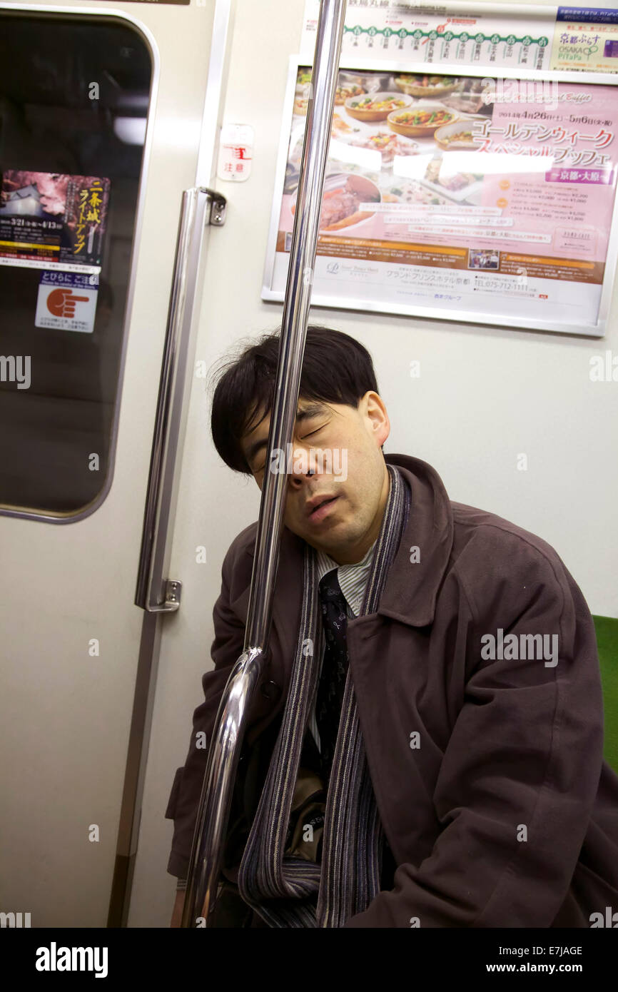 Exhausted japanese man sleeping on subway train, tired asian businessman, manager taking a nap. Kyoto, Japan, Asia Stock Photo