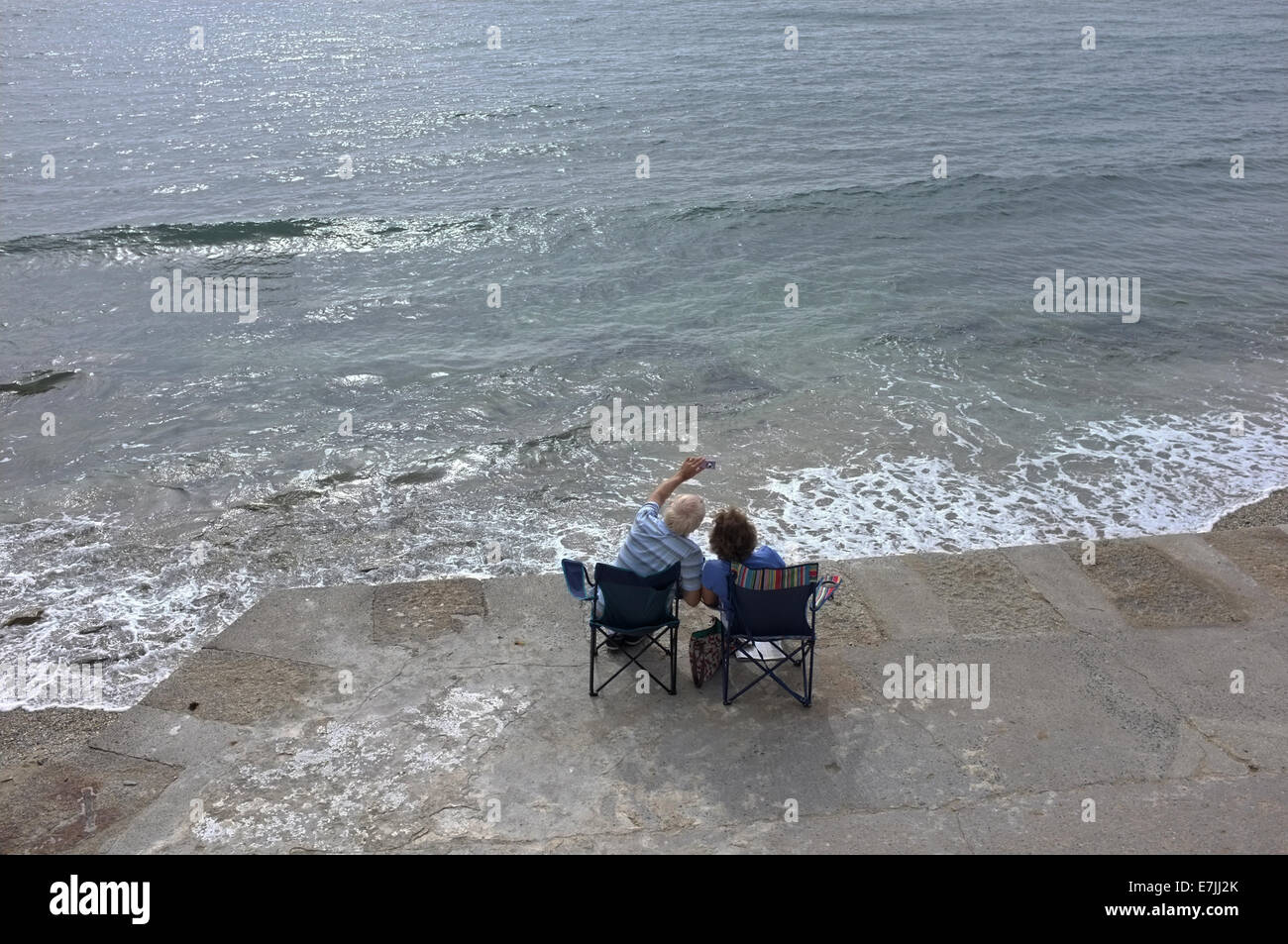 A couple sit by the sea in Falmouth, Cornwall taking a 'selfie' Stock Photo