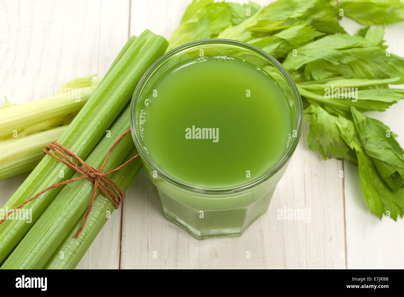 Green juice with celery stalk on white wood Stock Photo