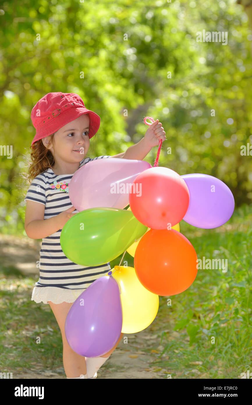 girl plays in summer park with colorful baloons Stock Photo
