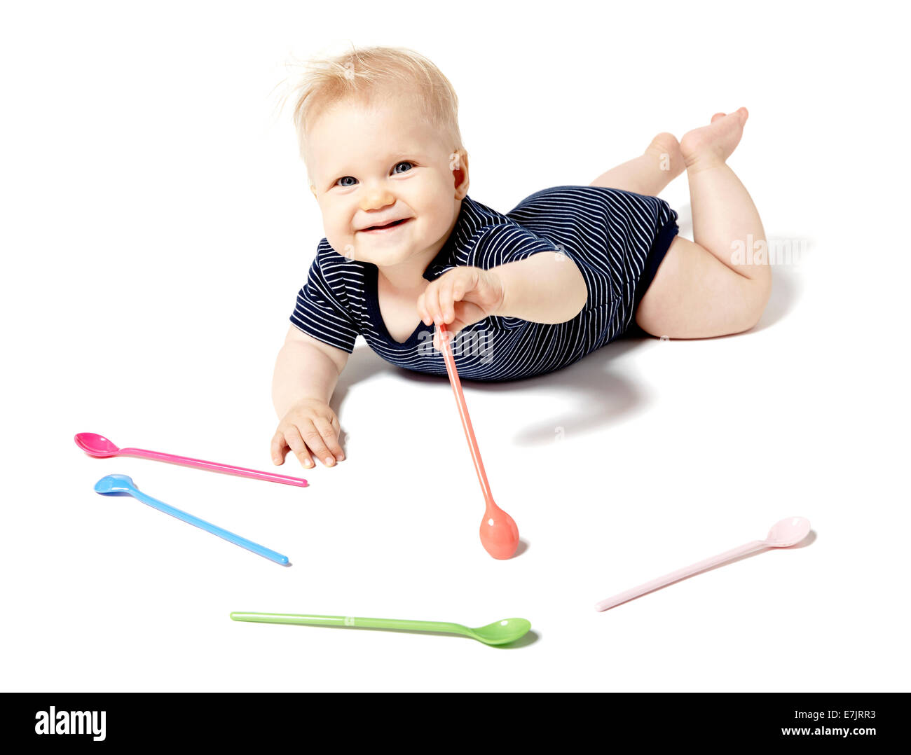 Seven months old baby picking spoons. Isolated on white background. Stock Photo