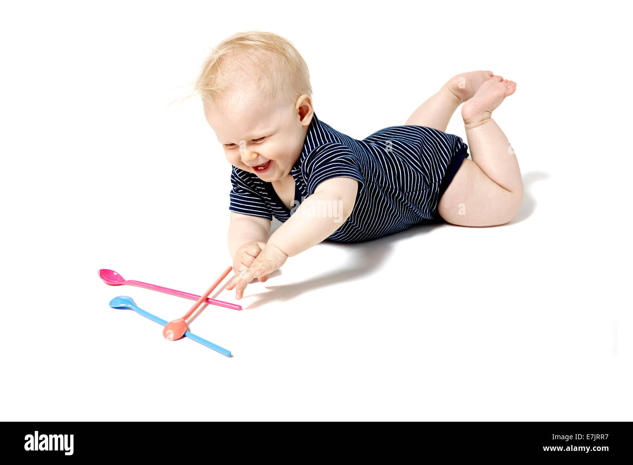 Seven months old baby playing with spoons. Isolated on white background. Stock Photo
