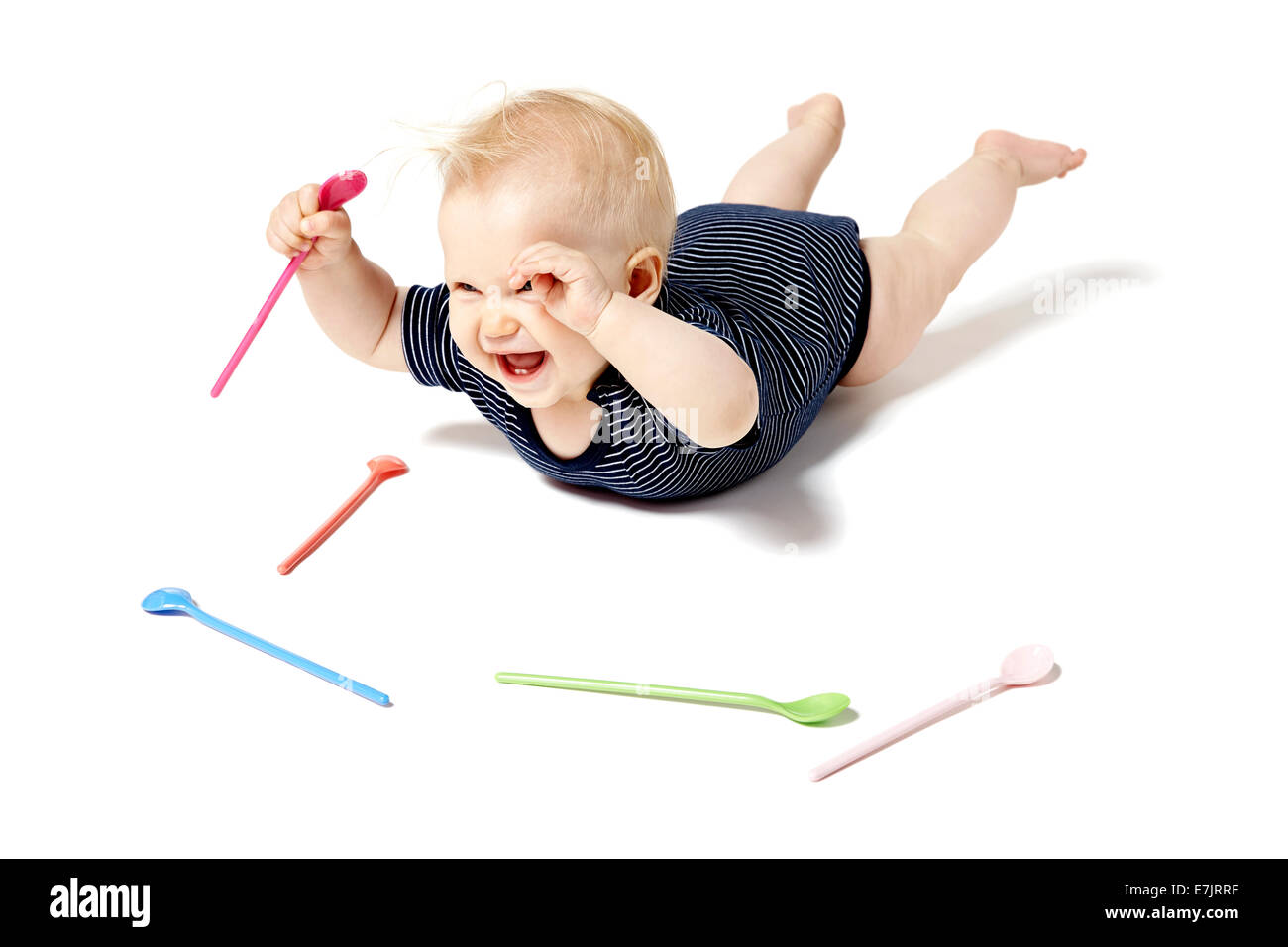 Seven months old baby picking spoon. Isolated on white background. Stock Photo
