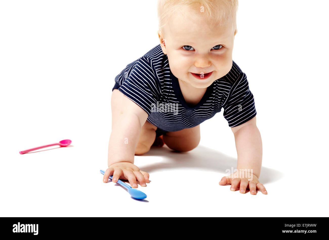 Happy baby girl crawling on her knees and looking at camera. Stock Photo