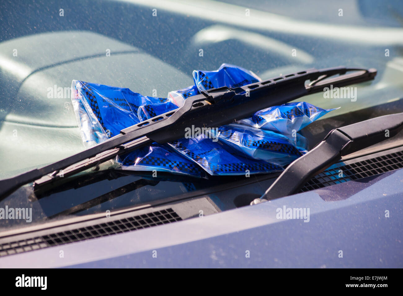 several parking tickets placed under car windscreen wipers for parking