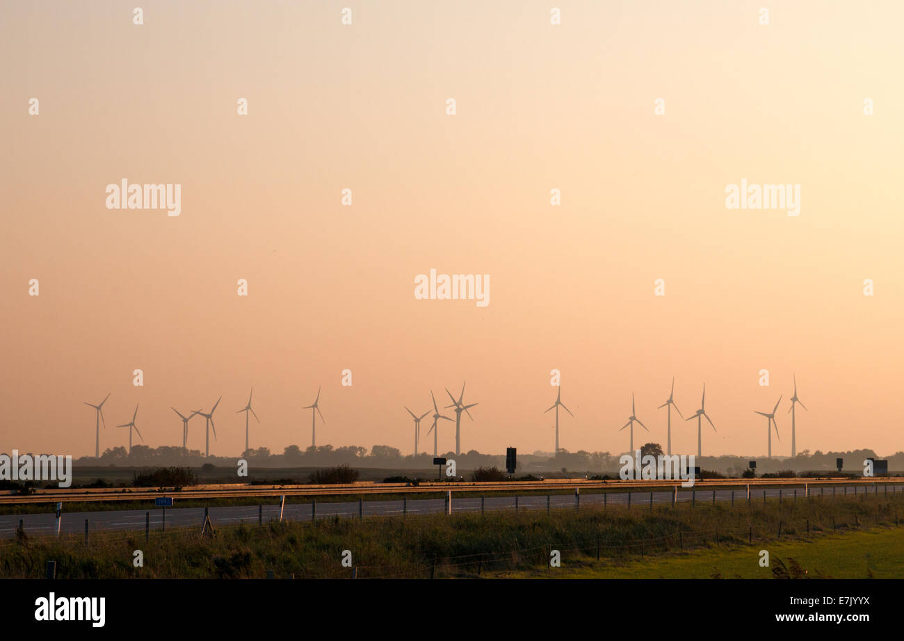 Windmills along the highway 31 in northern Germany near the city of Leer during sunset Stock Photo