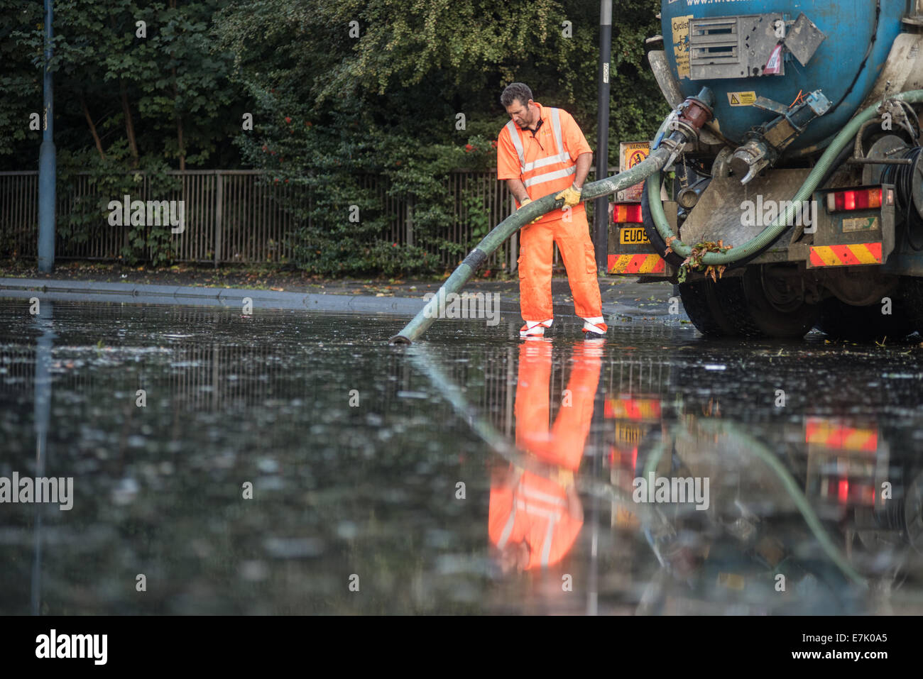 London, UK. 19th September, 2014. A workman using a suction pump in reflected in water as torrential rains cause floods and travel disruptions in East London.  Credit:  Piero Cruciatti/Alamy Live News Stock Photo
