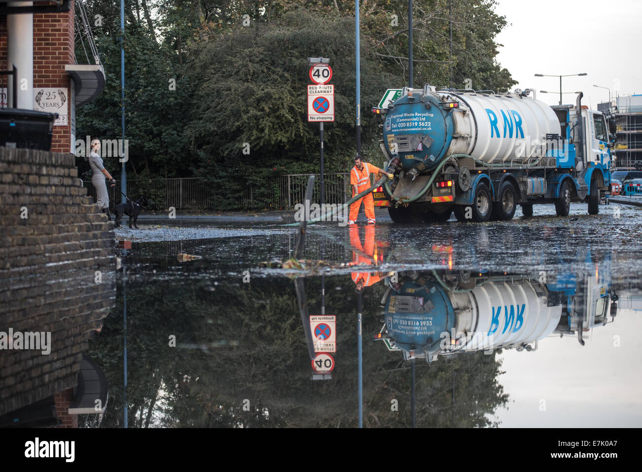 London, UK. 19th September, 2014. A workman using a suction pump in reflected in water as torrential rains cause floods and travel disruptions in East London. Credit:  Piero Cruciatti/Alamy Live News Stock Photo