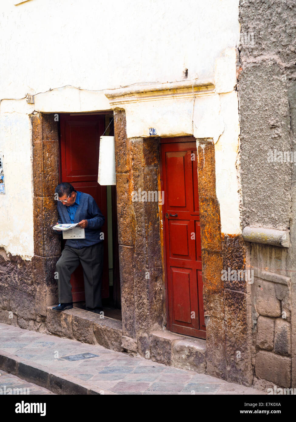 Man at the door reading the newspaper in Avenida Alta - Cusco, Peru Stock Photo