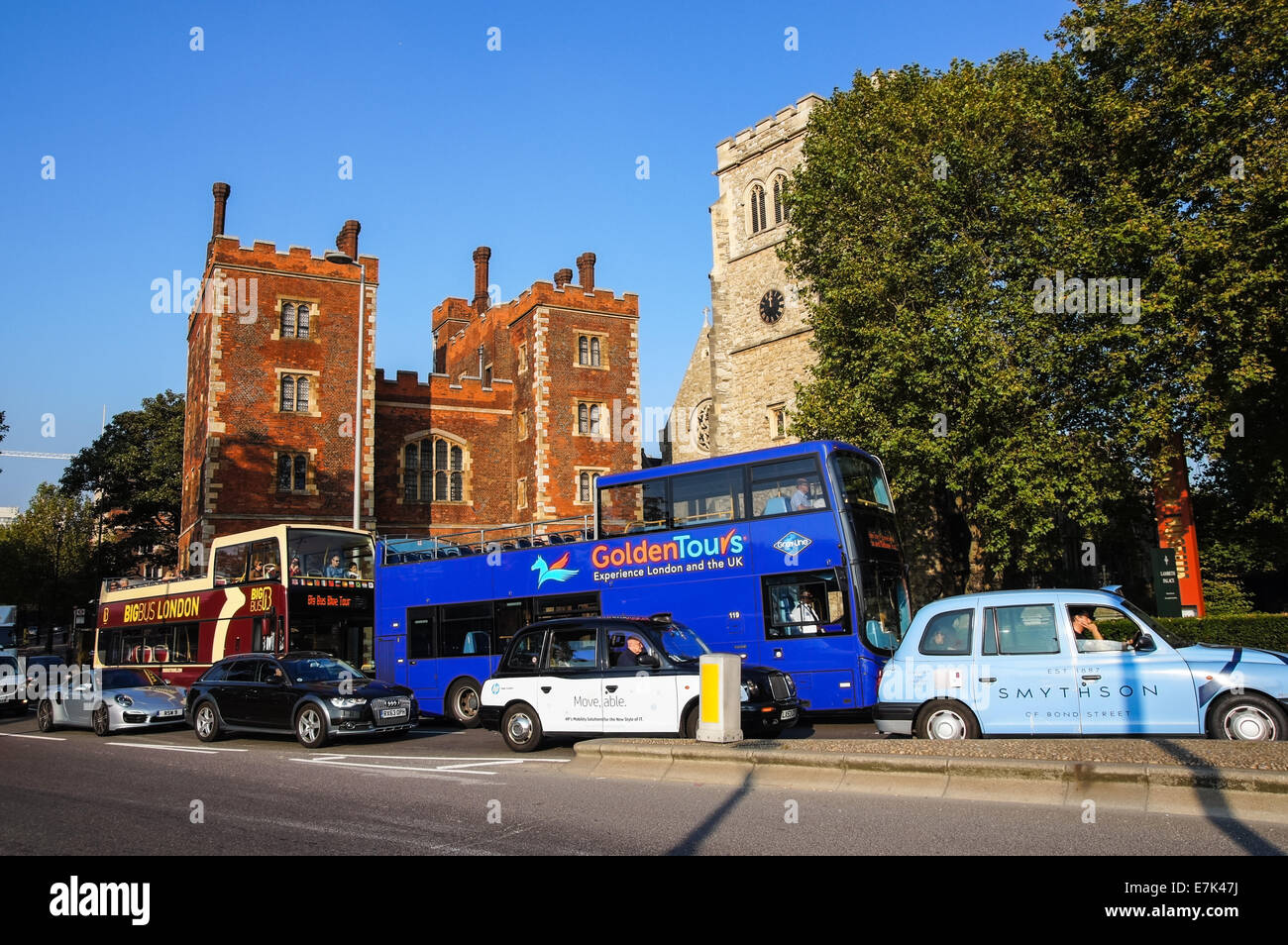Open-top sightseeing buses pass by Morton's Tower and Garden Museum in London England United Kingdom UK Stock Photo