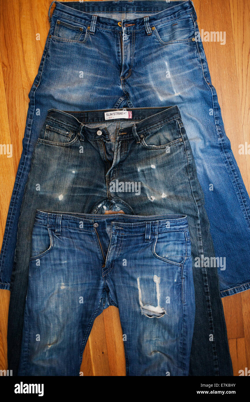 Three Faded Jeans From 2007 on Hardwood Floor Stock Photo