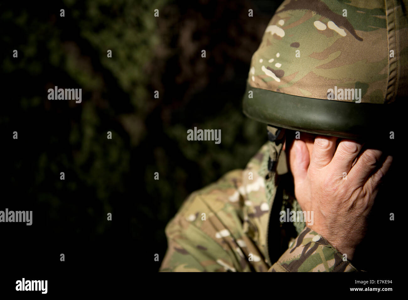 British soldier with his hands covering his face. Lit using a single spot light. Stock Photo