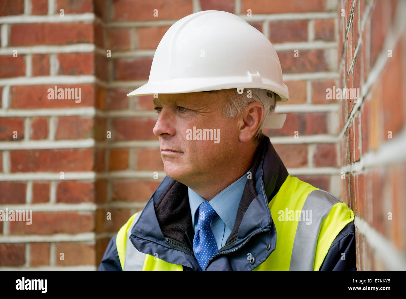 Head and shoulders portrait of a construction engineer against a brick wall background. Stock Photo