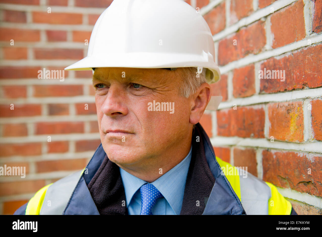Head and shoulders portrait of a construction engineer against a brick wall background. Stock Photo