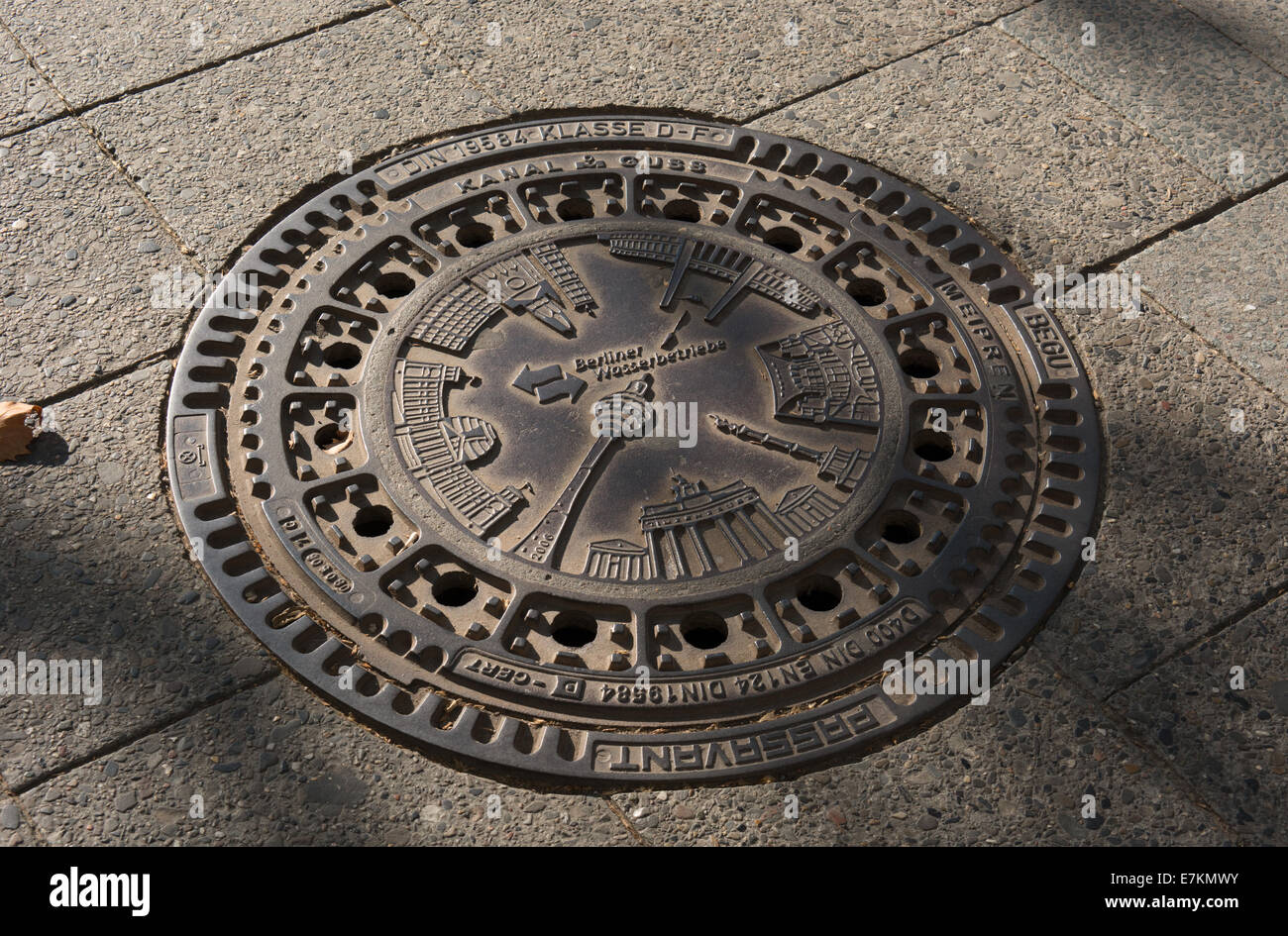 A man hole cover in the pavement of K damm Berlin. it shows some of the most famous sights in Berlin. Stock Photo